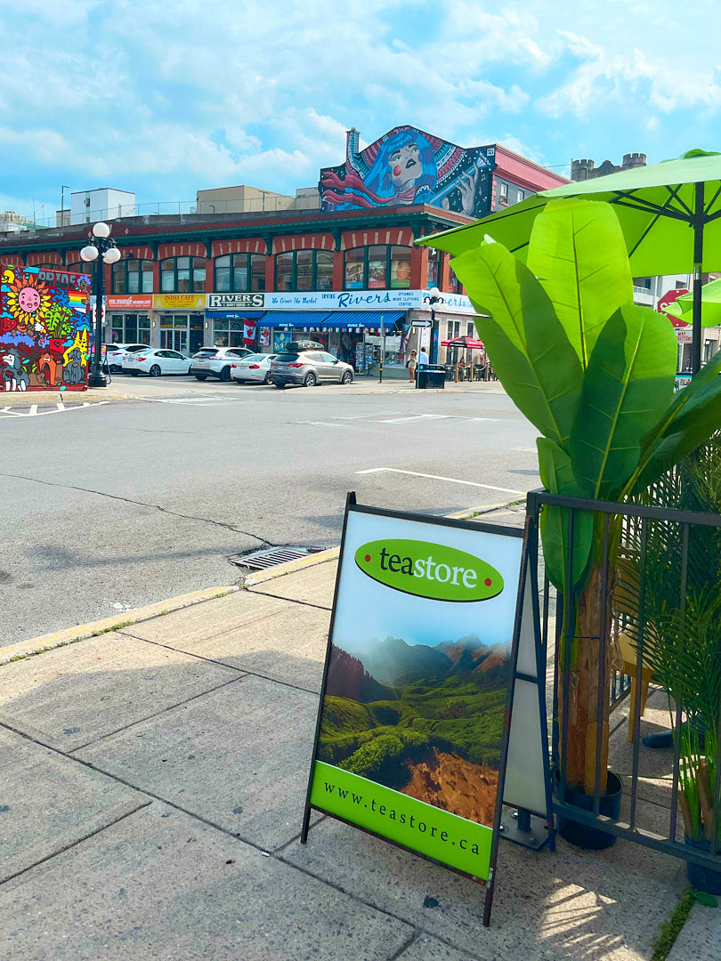 Teastore sign on a sidewalk with a city street in the background